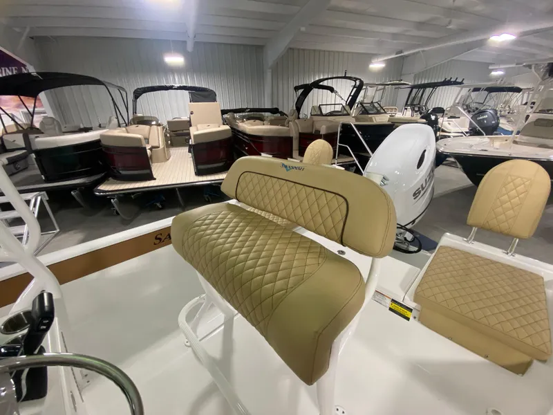 Slide: The Image of 2024 Savannah 210X boat interior with tan quilted seats in a showroom. - 10