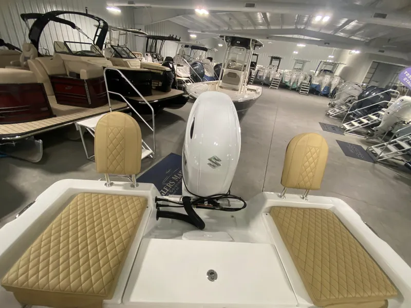 Slide: The Image of 2024 Savannah 210X boat interior with tan seats and white motor in showroom. - 5