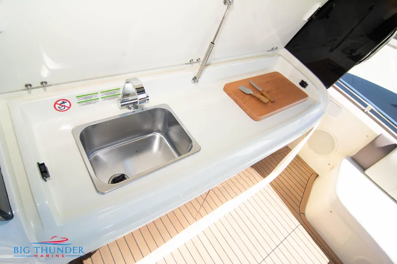 Slide: The Image of 2024 Invictus GT320 boat kitchen sink and cutting board area. - 27