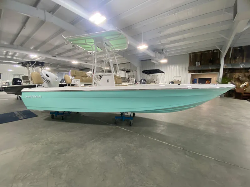 Slide: The Image of 2024 Savannah 210X boat in showroom, mint green hull, T-top, and outboard motor. - 3