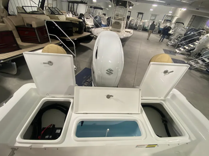 Slide: The Image of 2024 Savannah 210X boat with open storage compartments and Suzuki outboard motor in showroom. - 7