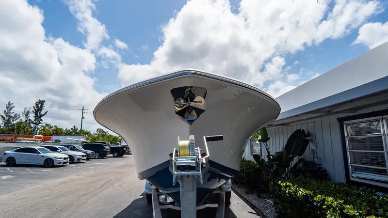 Slide: The Image of 2022 Tidewater 292CC Adventure boat on trailer, parked outdoors under a partly cloudy sky. - 2