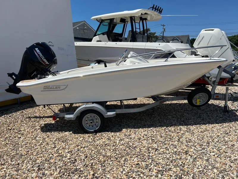 The Image of 2024 Boston Whaler 130 Super Sport boat on trailer, parked on gravel. - 0