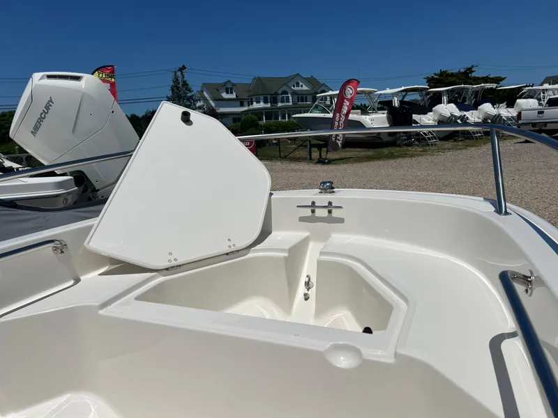 Slide: The Image of 2024 Boston Whaler 130 Super Sport boat with open storage compartment, outdoor display. - 10