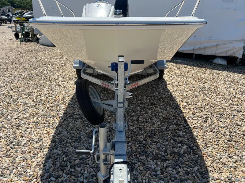 Slide: The Image of 2024 Boston Whaler 130 Super Sport boat on trailer, parked on gravel. - 11