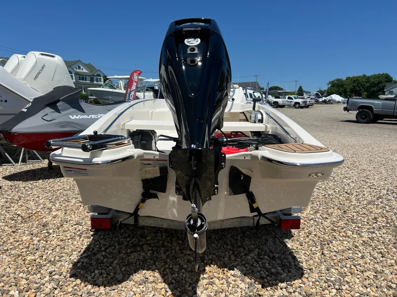 Slide: The Image of 2024 Boston Whaler 130 Super Sport boat, rear view with outboard motor, on gravel lot. - 2