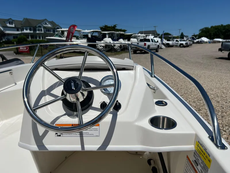 Slide: The Image of 2024 Boston Whaler 130 Super Sport boat dashboard with steering wheel and gauges. - 6