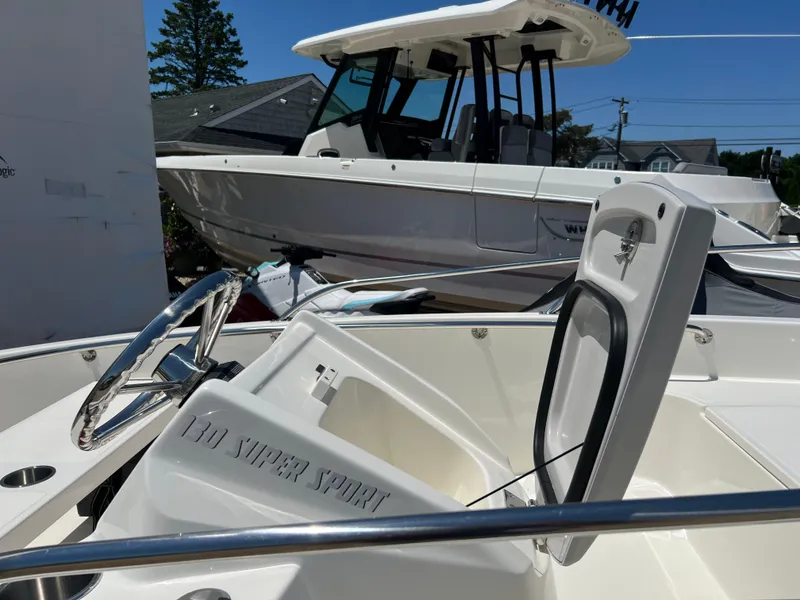 Slide: The Image of 2024 Boston Whaler 130 Super Sport boat interior with steering wheel and open storage compartment. - 8