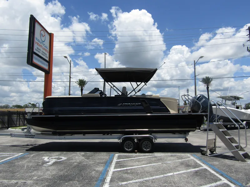 Slide: The Image of 2024 Starcraft RX 23 Q DC pontoon boat on a trailer in a parking lot. - 0