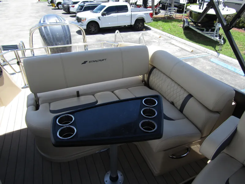 Slide: The Image of 2024 Starcraft RX 23 Q DC boat interior with beige seating and cupholder table. - 23