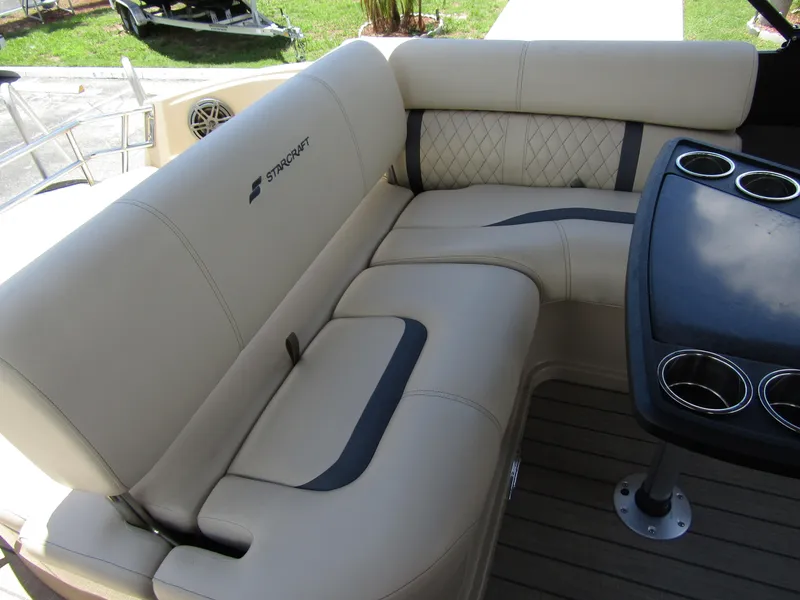 Slide: The Image of 2024 Starcraft RX 23 Q DC boat interior with beige leather seating and cup holders. - 24