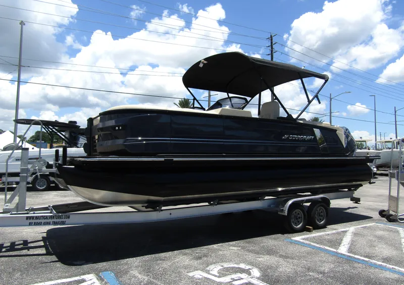 Slide: The Image of 2024 Starcraft RX 23 Q DC pontoon boat on a trailer under a blue sky. - 7