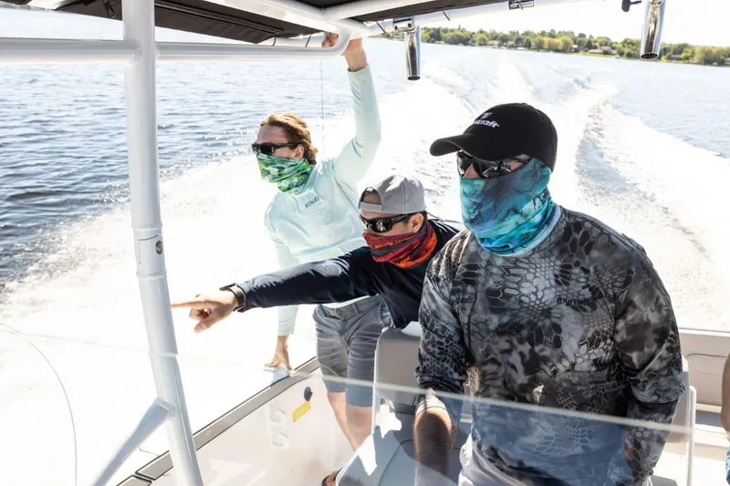 Slide: The Image of Three people on a 2024 Wellcraft 202 Fisherman boat, enjoying a sunny day on the water. - 12
