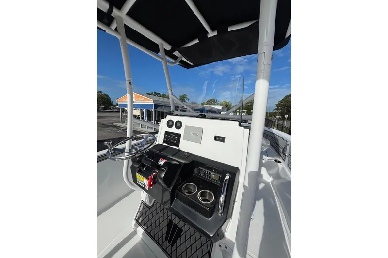 Slide: The Image of 2024 Wellcraft 202 Fisherman boat console with steering wheel and controls under a clear blue sky. - 4