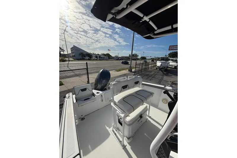 Slide: The Image of 2024 Wellcraft 202 Fisherman boat interior with seating and console, parked near a road. - 5