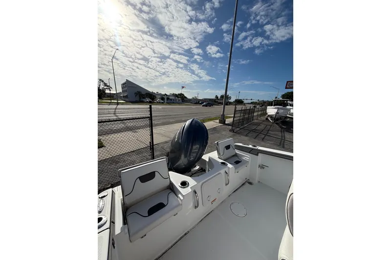 Slide: The Image of 2024 Wellcraft 202 Fisherman boat interior with seating and motor, under a sunny sky. - 6