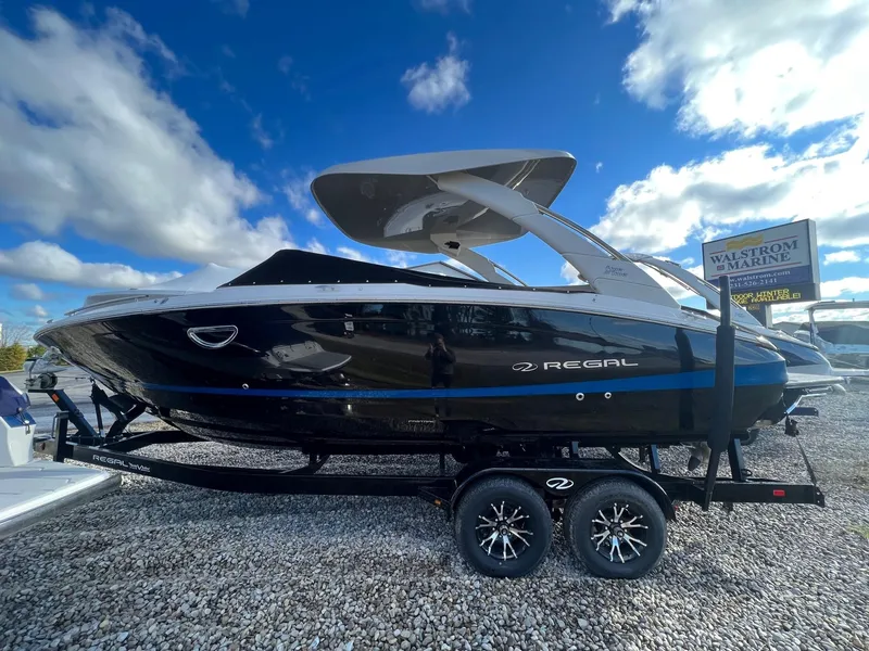 Slide: The Image of 2024 Regal LS6 Surf boat on trailer under blue sky. - 0