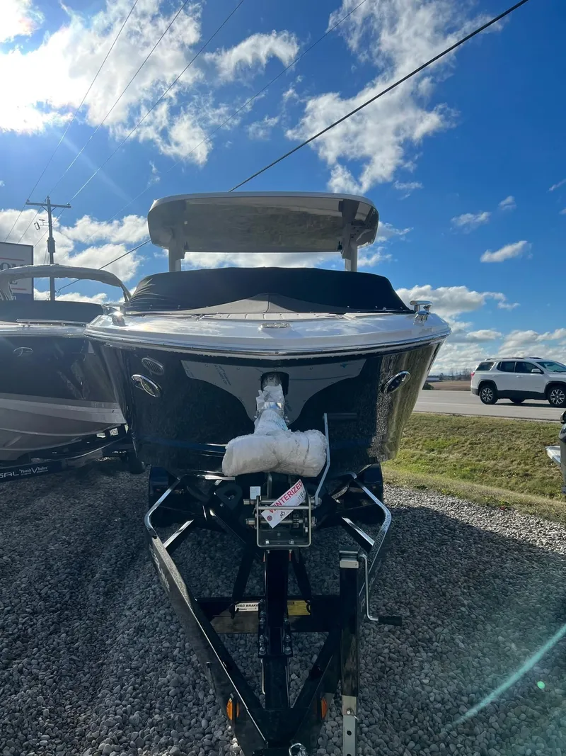 Slide: The Image of 2024 Regal LS6 Surf boat on trailer under blue sky. - 2