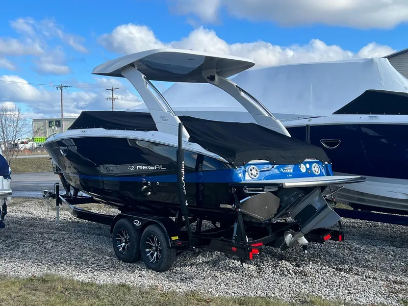 Slide: The Image of 2024 Regal LS6 Surf boat on trailer, sleek design, black and blue color scheme. - 3