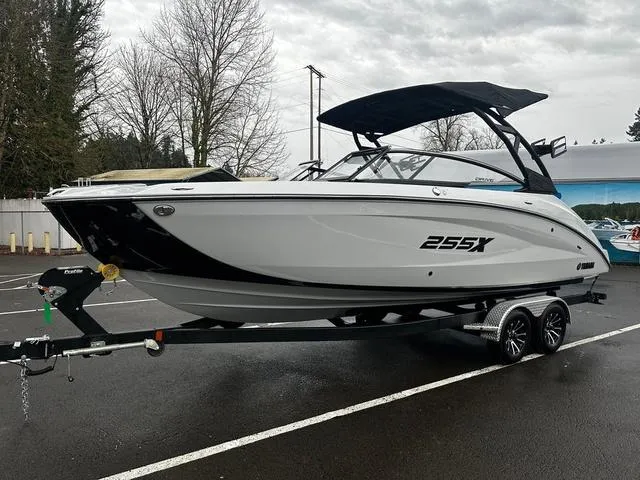 Slide: The Image of 2024 Yamaha Boats 255XD on trailer, sleek white design, black accents, and canopy. - 2