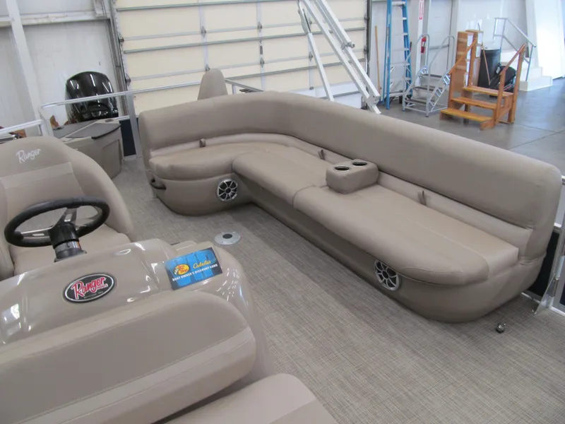 Slide: The Image of 2024 Ranger Reata 200F boat interior with beige seating and steering console in a showroom. - 7