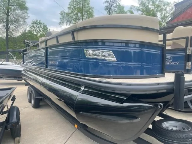 Slide: The Image of 2023 Regency 250 DL3 pontoon boat with blue exterior on a trailer. - 0