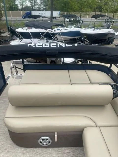 Slide: The Image of 2023 Regency 250 DL3 pontoon boat with beige seating and black canopy. - 4