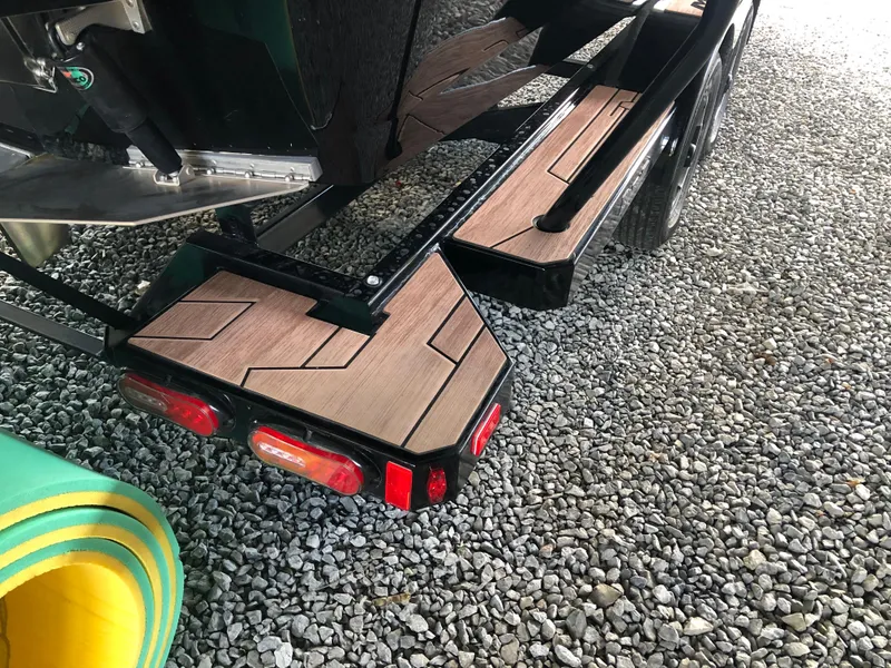 Slide: The Image of 2023 Moomba Makai boat trailer with wooden steps on gravel surface. - 18