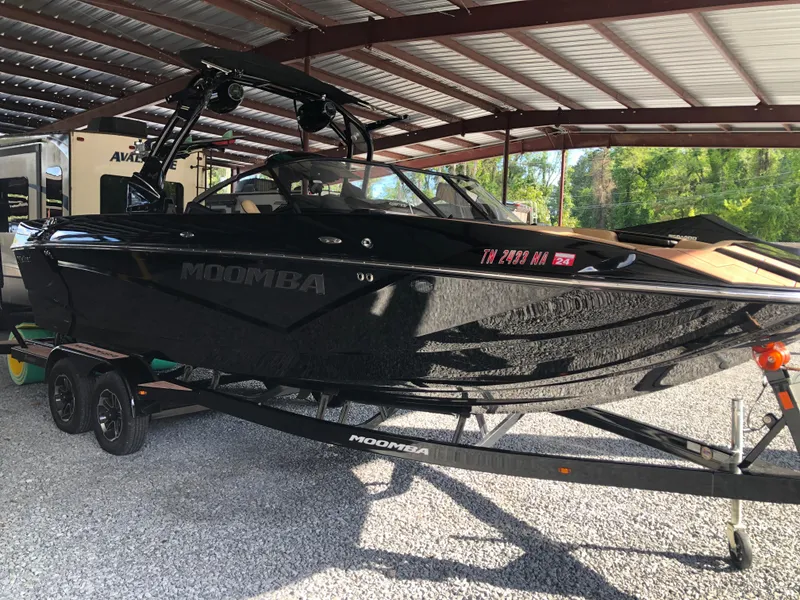 Slide: The Image of 2023 Moomba Makai boat in a covered storage area, black exterior, on a trailer. - 3
