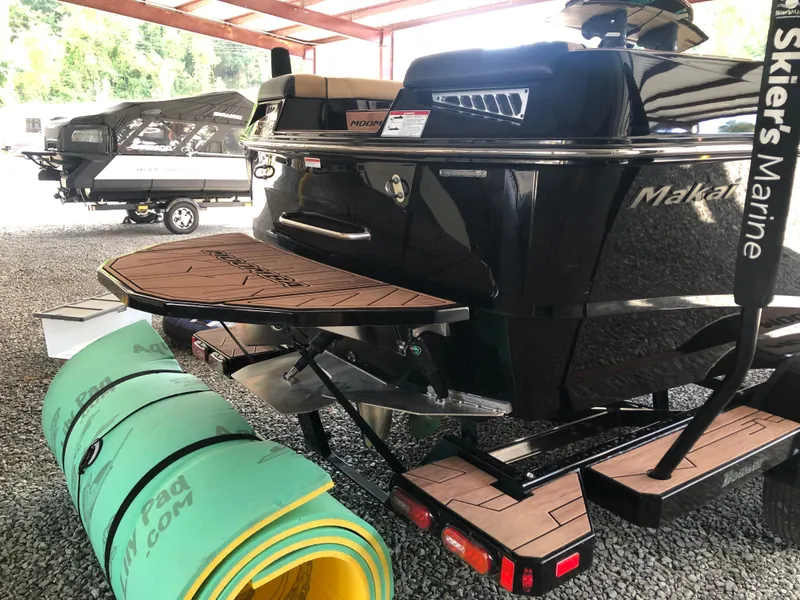 Slide: The Image of 2023 Moomba Makai boat with swim platform and trailer in a covered area. - 8