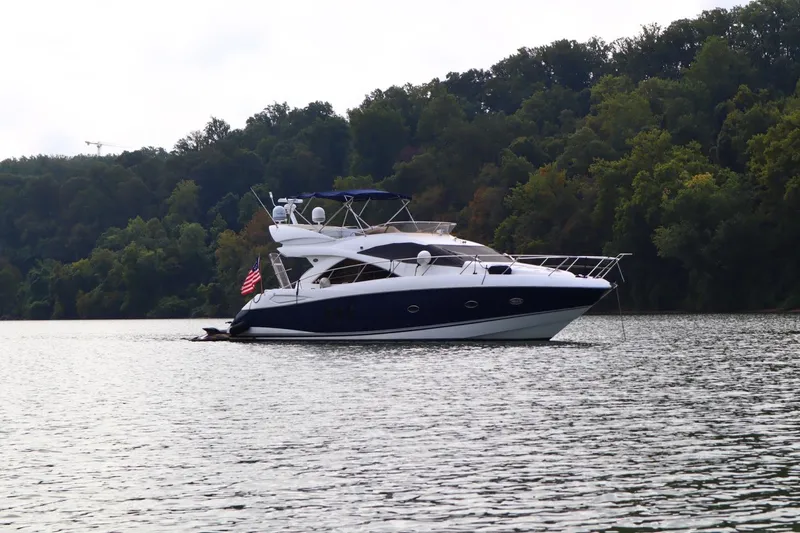 Slide: The Image of 2005 Sunseeker Manhattan 50 yacht cruising on a serene lake with forested shoreline. - 0