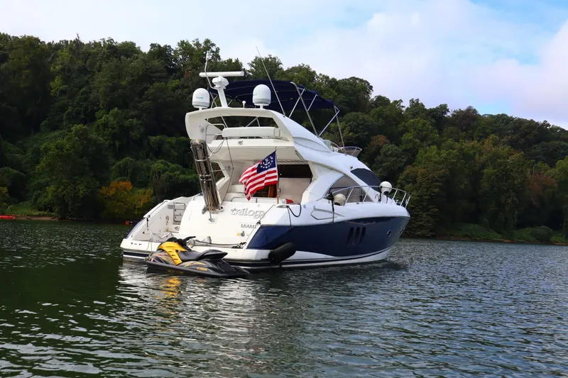 Slide: The Image of 2005 Sunseeker Manhattan 50 yacht anchored on a serene lake with lush greenery. - 1