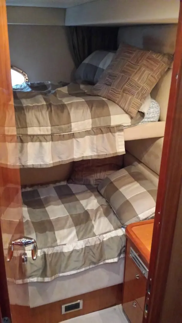 Slide: The Image of 2005 Sunseeker Manhattan 50 yacht cabin with bunk beds and plaid bedding. - 11