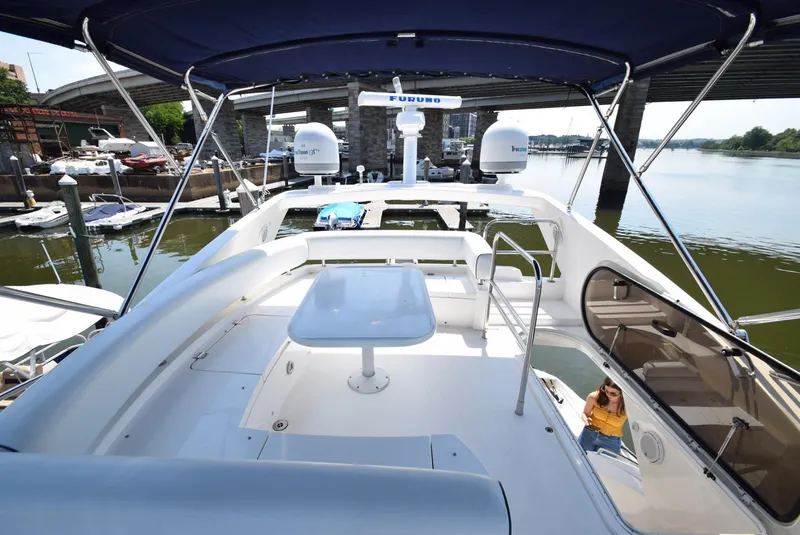 Slide: The Image of 2005 Sunseeker Manhattan 50 yacht flybridge with seating and table, docked near a bridge. - 18