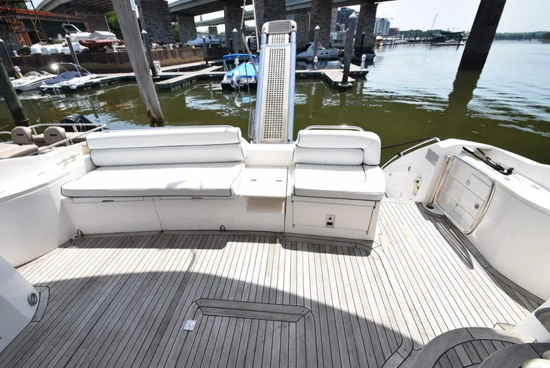 Slide: The Image of 2005 Sunseeker Manhattan 50 yacht with spacious deck and white seating at a marina. - 19