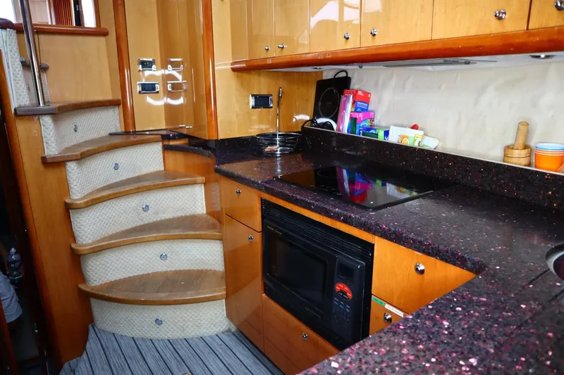 Slide: The Image of 2005 Sunseeker Manhattan 50 yacht kitchen with black countertops and wooden cabinetry. - 8