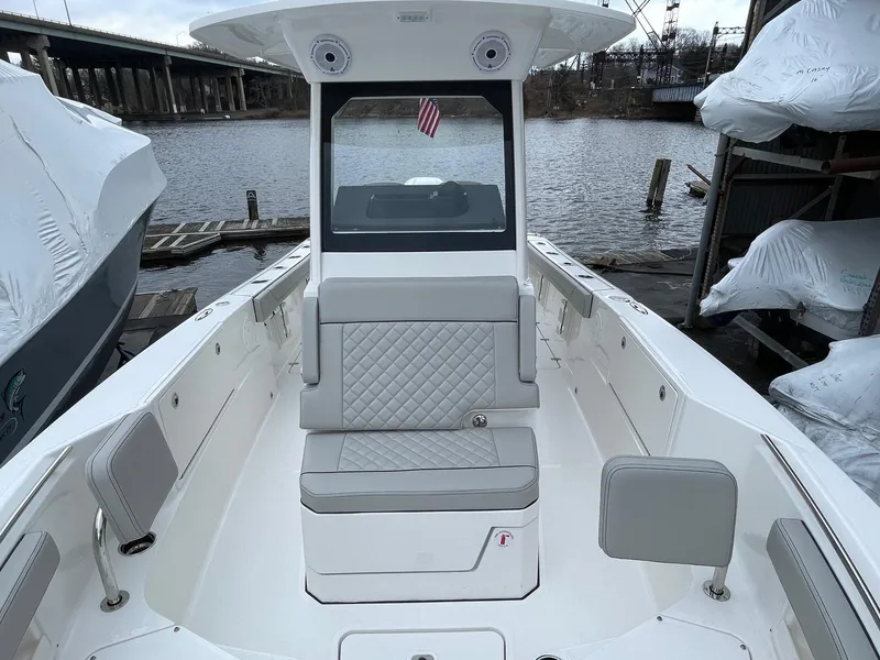 Slide: The Image of 2024 Pursuit S 248 Sport boat interior with gray seating, docked by the water. - 12