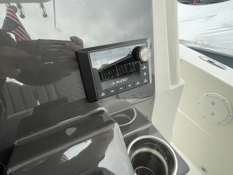 Slide: The Image of 2024 Pursuit S 248 Sport boat dashboard with JL Audio system and cup holders. - 19