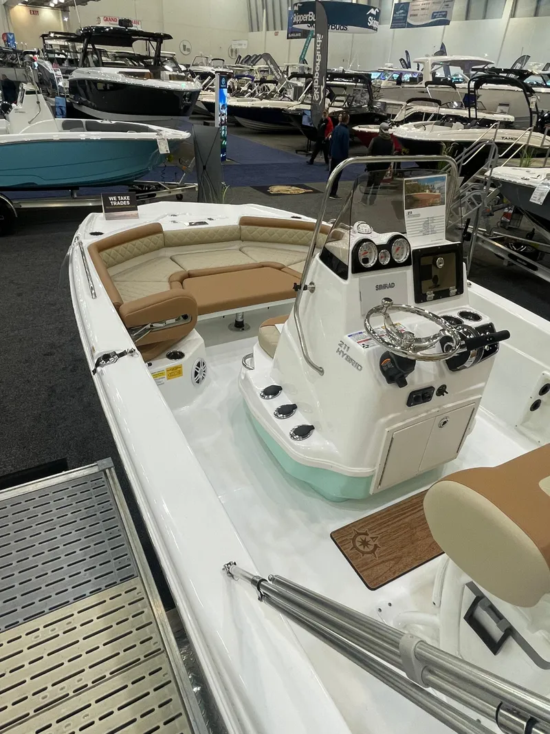 Slide: The Image of 2024 NauticStar 211 Hybrid boat on display at a boat show. - 2