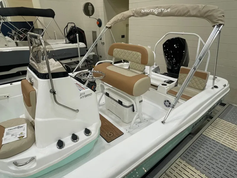 Slide: The Image of 2024 NauticStar 211 Hybrid boat with tan seating and white hull in showroom. - 3