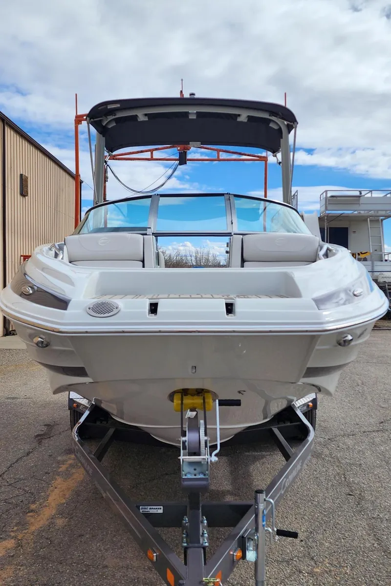 Slide: The Image of 2024 Crownline E235 boat on trailer, front view, outdoor setting. - 2
