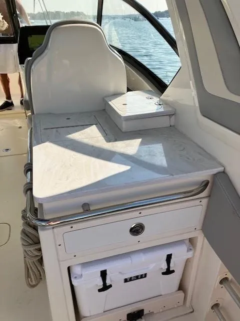 Slide: The Image of 2022 Scout 277 Dorado boat interior with seating and storage, docked by the water. - 10