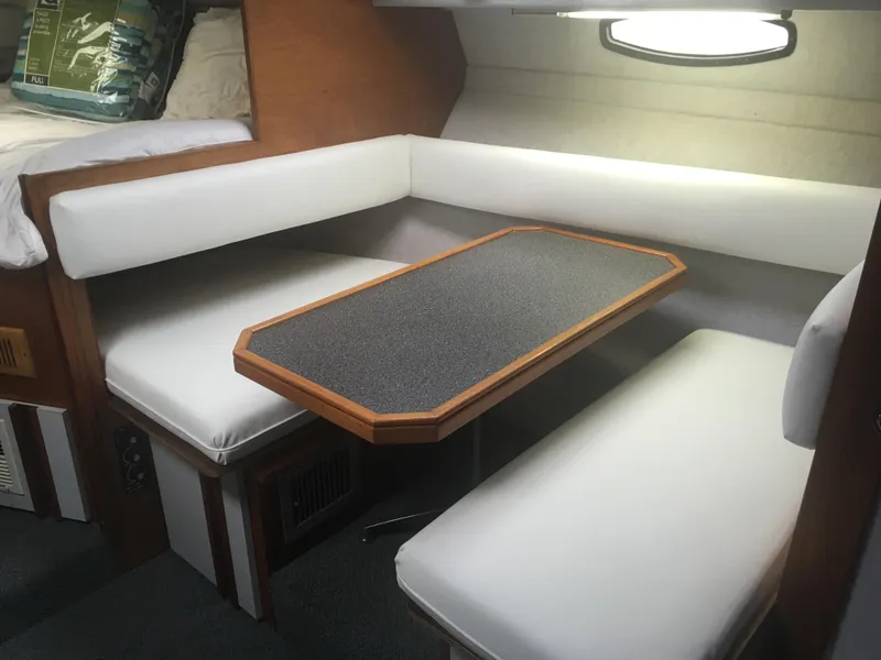 Slide: The Image of 1989 Cruisers Yachts 3060 Rogue interior with white seating and wooden table. - 3