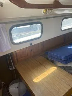 Slide: The Image of Interior of 1978 Bristol 29.9 Sloop with wooden table and blue cushions. - 6