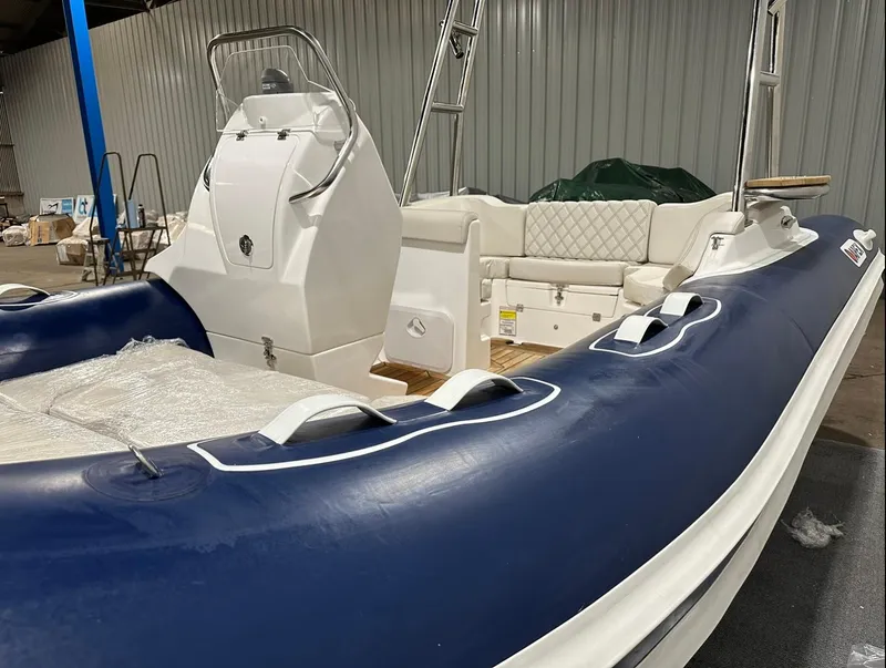 Slide: The Image of 2024 Apex A-18 Deluxe Tender boat with blue and white design in a warehouse. - 11