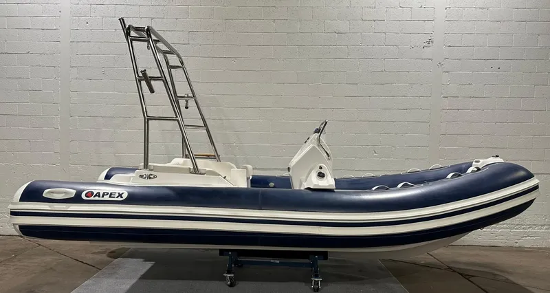 Slide: The Image of 2024 Apex A-18 Deluxe Tender boat with blue and white design in a showroom. - 5