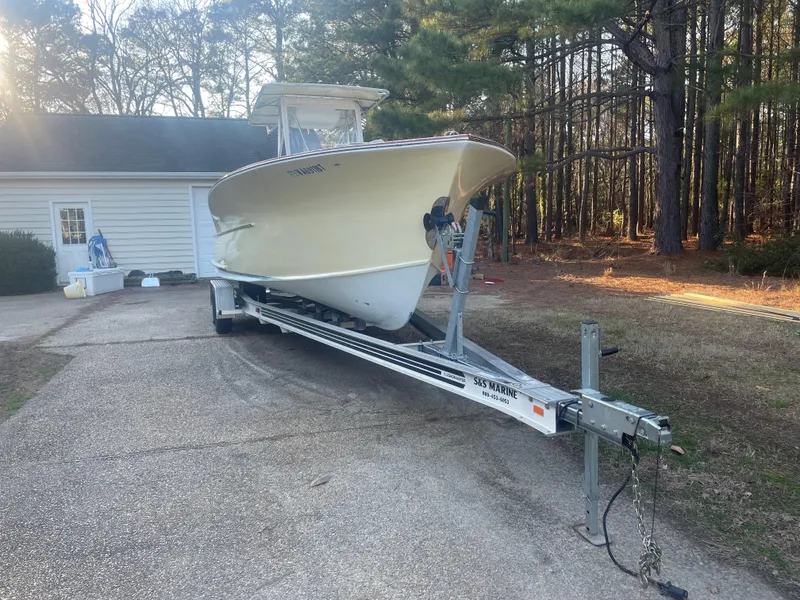 Slide: The Image of Custom Carolina Bandy 26' boat on trailer, parked near a house, surrounded by trees. - 7
