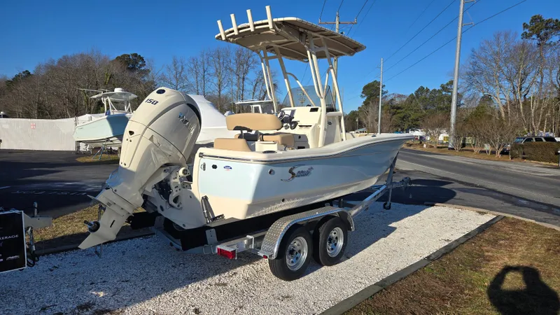 Slide: The Image of 2025 Scout 195 Sportfish boat on trailer, parked outdoors, featuring a powerful outboard motor. - 1