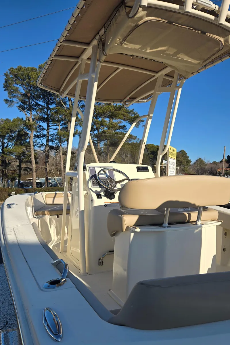 Slide: The Image of 2025 Scout 195 Sportfish boat with beige seating and canopy, parked outdoors. - 11