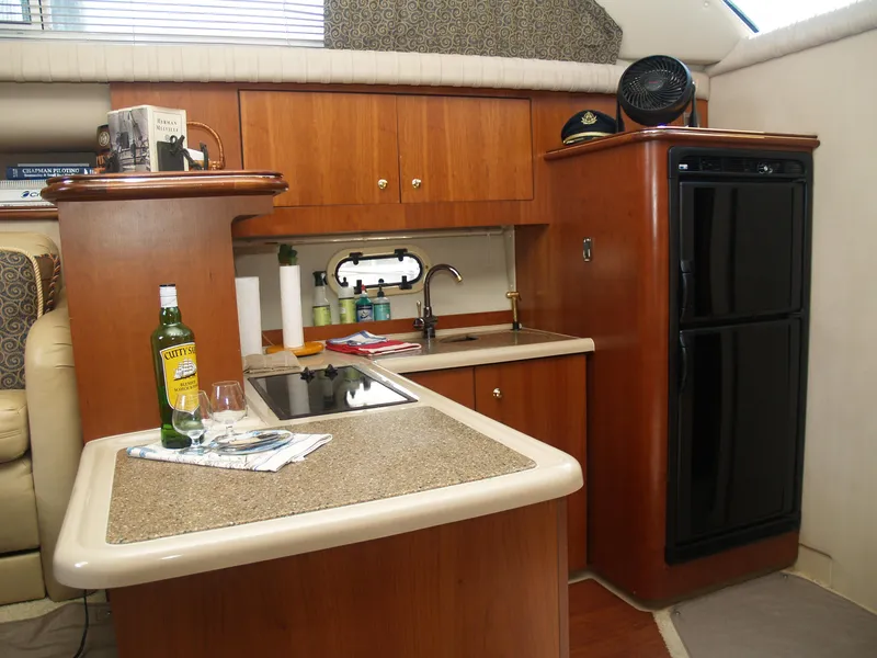Slide: The Image of 2001 Cruisers 3750 yacht kitchen with wood cabinetry, sink, and black refrigerator. - 12